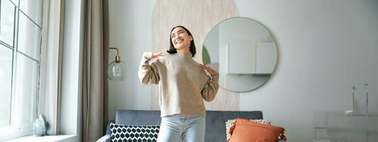 People and emotions. Joyful teen girl dancing in her room, feeling happy and carefree, concept of joy and satisfaction photo