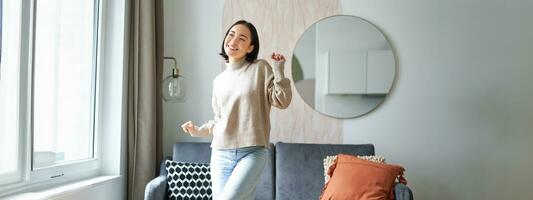 People and emotions. Joyful teen girl dancing in her room, feeling happy and carefree, concept of joy and satisfaction photo