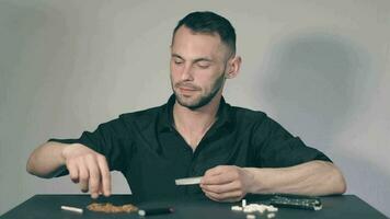 Man in Black Clothing is Rolling a Hand Made Cigarette Using Papers, Filters and Tobacco. A Way to Save on Tobacco Products. Tobacco Product Economy Concept. Middle Angle VIew, Static Shot video