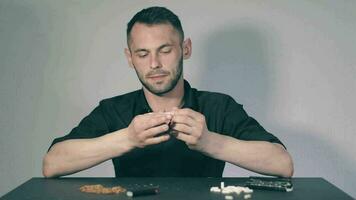 Man in Black Clothing is Rolling a Hand Made Cigarette Using Papers, Filters and Tobacco. A Way to Save on Tobacco Products. Tobacco Product Economy Concept. Middle Angle VIew, Static Shot video