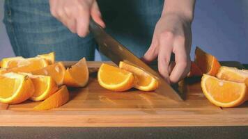 mujer en azul pantalones es corte grande jugoso naranja a hogar. ama de casa es preparando ingredientes para alguna cosa dietético. sano comida concepto. estático de cerca Disparo video