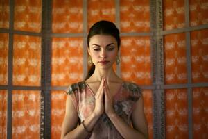 AI generated a woman with her hands clasped together, possibly praying or meditating in front of an orange wall. She appears to be in a contemplative and focused state, seeking solace or enlightenment. photo