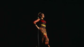 an Asian woman stands confidently while wearing a batik costume and black scarf video