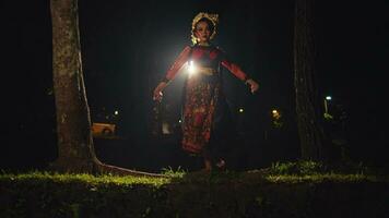 an Asian woman walks while dancing in front of the lights while wearing a bun in her black hair with gold accessories video