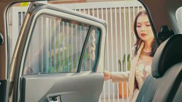 un asiatique femme dans une veste et une marron sac est équitation dans une voiture dans une se ruer video