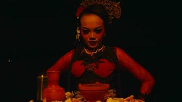 un asiático mujer es sentado en frente de el ritual ofrendas con un astuto y de miedo expresión video