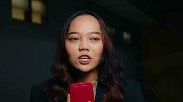 ein asiatisch Frau mit braun Haar und ein schwarz Mantel Gespräche zu das Kamera mögen ein Reporter video