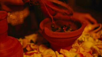 a woman's hand is putting coconut fiber into a jug to be burned during the ritual video