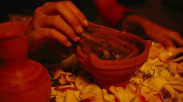 un mujer mano es poniendo Coco fibra dentro un jarra a ser quemado durante el ritual video