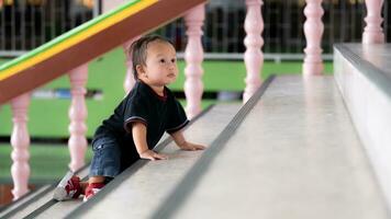 pequeño bebé chico alpinismo arriba escaleras.1 año antiguo adorable asiático niñito desarrollo. niño peligro y seguridad. el concepto desarrollo. foto