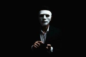 Unknown businessman wearing mask with covered face using mobile phone makes an anonymous call intimidating and threatening the interlocutor on dark background. hacker callcenter concept. photo