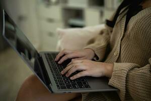 Top view. Asian freelance woman smile lying relax and typing on keyboard and working on laptop on sofa couch. Entrepreneur woman working for her business at living room home. Business work home. photo