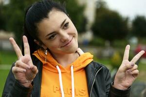 The girl on the street shows the symbol of victory in her hands photo