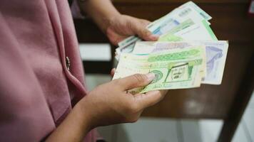 4K video footage.  Unidentified woman in hijab holding paper currency from different countries. Concept of investment, money exchange, bribes or corruption. Selective focus.