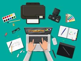 Designer workplace. Illustrator desktop with tools. Laptop pc, photo camera, mouse, glasses, notes, pen, printer. Sketch on paper blank. Hands work graphic tablet. Vector illustration in flat style