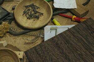 Craft carpentry workshop with variety of wooden pieces and planks, hand tools and wooden work bench in the foreground. Joinery with workbench and lots of wood. Carpenters table with furniture details photo