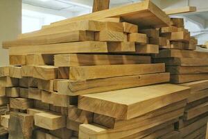 Close-up of wooden planks at lumber warehouse. Storage shelves with panel in lumberyard. Background of boards on shop. Processed timber blocks products in market. Raw wood drying in carpenter workshop photo