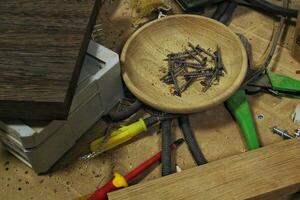 Craft carpentry workshop with variety of wooden pieces and planks, hand tools and wooden work bench in the foreground. Joinery with workbench and lots of wood. Carpenters table with furniture details photo