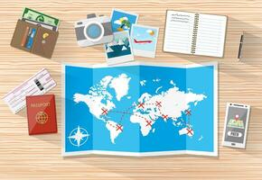 Wooden table with paper map of world and tourist equipment. passport, airplane ticket, notebook, smartphone with navigation application, photo camera photos, wallet. vector illustration in flat design