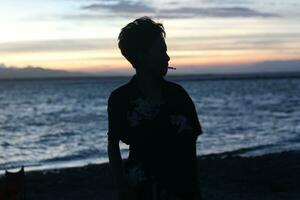 Silhouette of a young man standing by the lake enjoying the sunset. peaceful atmosphere in nature photo