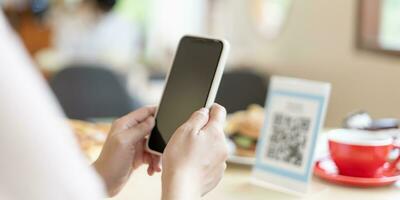 Woman use smartphone to scan QR code for order menu in cafe restaurant with a digital delivery. Choose menu and order accumulate discount. E wallet, technology, pay online, credit card, bank app. photo