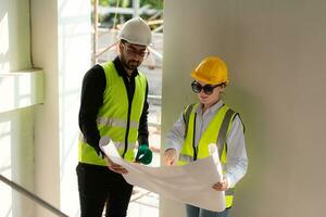 Engineer and architect working on the construction site, double-checking plans and process. photo