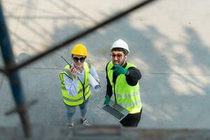 Overhead view on a building site, an engineer and architect are discussing on a laptop. photo
