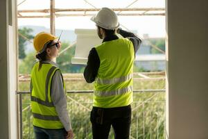 Engineer and architect working on the construction site, double-checking plans and process. photo