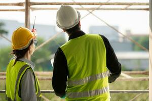 Engineer and architect working on the construction site, double-checking plans and process. photo