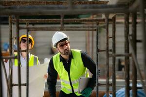 Engineer and architect working on the construction site, double-checking plans and process. photo