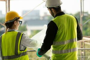 Engineer and architect working on the construction site, double-checking plans and process. photo