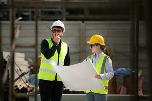 Engineer and architect working on the construction site, double-checking plans and process. photo