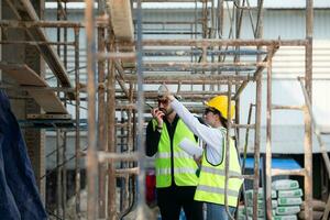 Engineer and architect working on the construction site, double-checking plans and process. photo