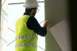 ingeniero o arquitecto trabajando en el construcción sitio, doble revisión planes y proceso. foto