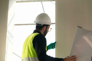 ingeniero o arquitecto trabajando en el construcción sitio, doble revisión planes y proceso. foto