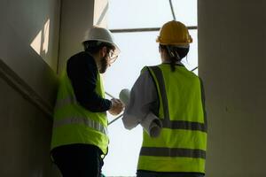Engineer and architect working on the construction site, double-checking plans and process. photo