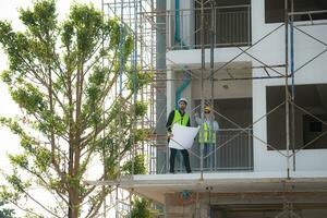 Engineer and architect working on the construction site, double-checking plans and process. photo