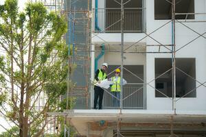 Engineer and architect working on the construction site, double-checking plans and process. photo