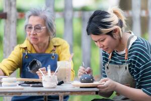 In the pottery workshop, an Asian retired couple is engaged in pottery making and clay painting activities. photo