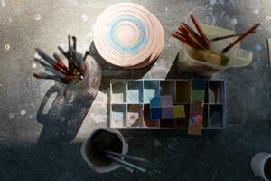 pintar cepillos en vaso tarro en de madera mesa en el jardín para preparando a pintar cerámica. foto