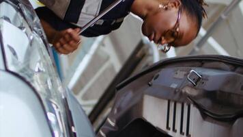 Vertical video Trained serviceman in repair shop using torque wrench to tighten screws after checking car parameters during maintenance. Expert using professional tool in garage to mend vehicle, ground level shot