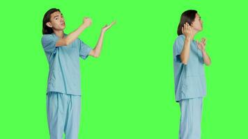 Working in healthcare medical industry, asian nurse conducting ad campaign against greenscreen background. Nurse in uniform points left or right sides, displaying fresh advertising. video