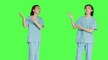 Asian specialist does advertisement against greenscreen background, working in healthcare medicine industry. Nurse wearing uniform and showing new marketing ad, left right sides. video