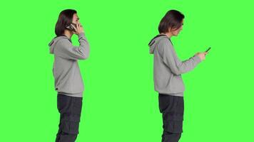 Young man answering call and texting in studio with greenscreen backdrop, talking remotely on smartphone and messaging. Asian male model using mobile phone for different actions. video