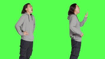 Person feeling exhausted and yawning after not sleeping enough, posing with fatigue and low energy over greenscreen. Young guy being extremely sleepy and tired, falling asleep standing. video