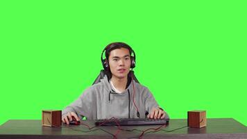 POV of man playing online videogames at computer while he enjoys gameplay with his friends, using headphones at desk. Asian player having fun with adventure game at workstation, greenscreen. video