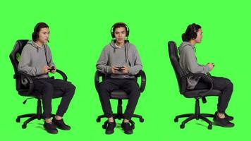Player enjoys roleplaying battle against greenscreen backdrop while playing online games with controller. Asian guy delights in web video games, gaming enthusiast with excellent focus.
