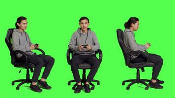 Asian adult enjoying video games over full body greenscreen, using controller and having fun with colleagues on online gaming contest. Young guy gamer playing multiplayer gameplay.