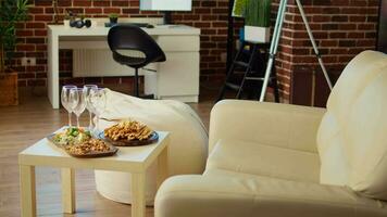 Empty stylish cozy apartment living room with crackers, peanuts and cheese on charcuterie board, awaiting guests to arrive for social event. Elegant house interior with homely vibe, close up video