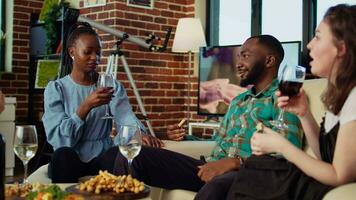 African american man captivating audience at birthday party with enthralling story in cozy apartment. BIPOC group of people listening to their friend sharing interesting tale in living room video